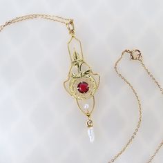 "A sparkling red synthetic ruby contrasts with two-tone gold hues on this vintage 1930s Art Deco 10k solid gold lavalier pendant. The airy elegant petite pendant has a flowing linear carved trim shape. A slightly different hue of gold with leaf motif bridges the frame. Delicate filigree surrounds the round faceted 4mm syn. red ruby. A 2mm seed pearl is mounted below. A white baroque 6.2mm long pearl dangles at the very bottom. The pendant tested as 10k gold purity (no hallmarks found). The penda Dainty Jewelry With Vintage Charm And Flower Pendant, Dainty Vintage Charm Flower Pendant Jewelry, Dainty Flower Pendant Jewelry With Vintage Charm, Dainty Flower Pendant With Vintage Charm, Elegant Vintage Charm Jewelry, Vintage Charm Art Deco Jewelry For Formal Occasions, Art Deco Vintage Charm Jewelry For Formal Occasions, Formal Art Deco Jewelry With Vintage Charm, Art Deco Jewelry With Vintage Charm For Anniversary