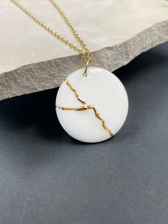 "Handmade porcelain kintsugi pendant necklace. Inspired by KINTSUGI. A perfect anniversary gift or encouragement gift. Kintsugi is a Japanese art of repairing broken pottery with gold. Ceramics once broken are glued back together with lacquer and finished with gold to bring beauty to what was once shattered. Kintsugi honors brokenness and challenges in life -- it celebrates beauty in the broken. This metaphor we can apply to ourselves. We can mend and transform what has broken us, and we can fin Minimalist White Keepsake Necklace, White Round Pendant Necklaces For Anniversary Gift, White Round Pendant Necklace For Anniversary, Minimalist Handmade Necklace For Keepsake, Minimalist White Jewelry For Anniversary, Minimalist White Jewelry For Anniversary Gift, Minimalist Handmade Keepsake Necklace, Kintsugi Necklace, Kintsugi Aesthetic