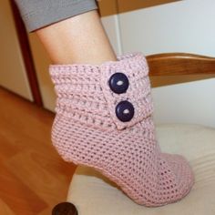 a close up of a person's foot wearing crocheted shoes with buttons