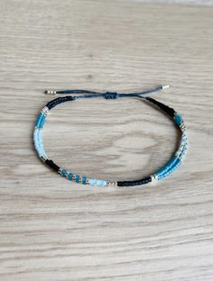 A delicate and elegant string bracelet made of two strands of black, silver and blue miyuki beads. ☆ ☆ ☆ SIZING☆ ☆ ☆ This bracelet is easily adjustable thanks to a macrame slide knot. It should fit most adults and teens but please message me if you think you need a smaller or larger fit. It is about 5 inches when fully tightened and about 9 inches when expanded. ☆ ☆ ☆ TAKING CARE OF YOUR BRACELET ☆ ☆ ☆ This bracelet is waterproof but it is best to avoid prolonged exposure with salt, chlorine, pe Minimalist Blue Beaded Bracelets As Gift, Minimalist Blue Beaded Bracelet As Gift, Minimalist Blue Bracelets With Tiny Beads, Minimalist Blue Adjustable Beaded Bracelet, Blue Multi-strand Bracelets With Tiny Beads, Miyuki Bracelet, Cord Jewelry, Miyuki Beads, Minimalist Bracelet