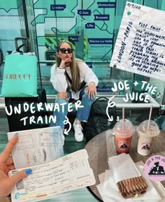 a woman sitting at a table in front of a sign that says underwater joe the train & juice