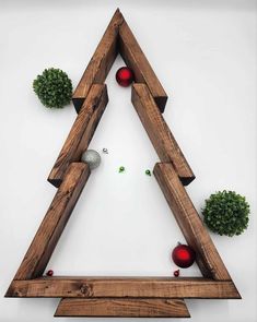 a triangle made out of wood with balls in the middle and greenery around it