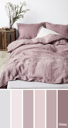 a bed with pink sheets and pillows on top of it in front of a white wall