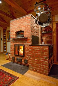 an open fire place in the middle of a room with wood flooring and brick walls