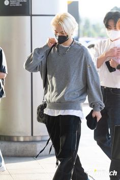 a woman wearing a face mask walks down the street with her hand in her mouth