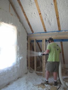 a man sprays foam on the walls of a room