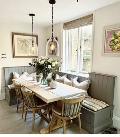 a dining room table and bench with flowers in vases on the centerpiece next to it