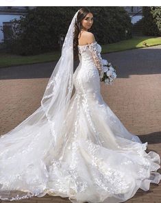 a woman in a wedding dress is standing on the sidewalk with her veil blowing in the wind