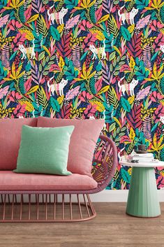 a colorful wallpaper with unicorns and palm leaves on the walls is next to a pink couch