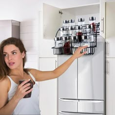 a woman holding a cup in front of a refrigerator