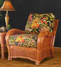 a wicker chair with a floral upholstered seat and footstool in front of a black wall