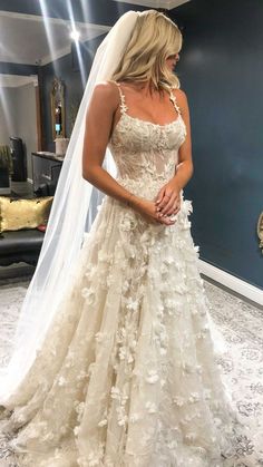 a woman in a wedding dress looking down at her veil and posing for the camera