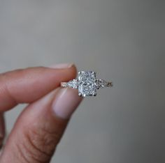 a woman's hand holding a three stone diamond ring