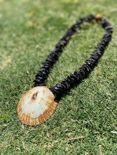 This handmade lei is a unique treasure crafted with care, featuring kukui nut shell pieces intricately woven together to create a stunning base. At its center lies a magnificent big opihi shell, sourced from the pristine shores of Hawaii, adding a touch of natural elegance and a sense of island charm. This one-of-a-kind creation is a perfect gift for any occasion, symbolizing beauty, tradition, and the spirit of aloha. Handmade Spiritual Shell, Handmade Brown Shell-shaped Necklace, Handmade Brown Shell Necklace, Artisan Handmade Shell Craft, Brown Shell-shaped Jewelry For Vacation, Brown Shell Jewelry For Vacation, Traditional Adjustable Shell Necklace, Handmade Shell Necklace, Kukui Nut Lei