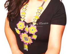 a woman wearing a black shirt with yellow and pink flowers on it's chest