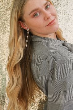 a woman with long blonde hair and earrings on her head is leaning against a wall