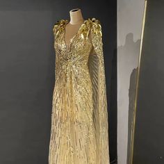 Golden Elegance: The gold hue exudes opulence and regal charm, ensuring you make a memorable and stylish statement. Sparkly Beaded Cape: The cape with sparkly bead embellishments adds a touch of glamour and sophistication, enhancing the gown's allure. Ideal for Wedding Parties: Tailored for wedding parties, ensuring you exude charm and grace amidst the celebration. Perfect for Formal Events: Equally fitting for various formal occasions, making it a versatile addition to your formal wardrobe. Lux Gold Beaded Dress, Beaded Cape, Reception Gown, Gold Gown, Alternative Bridal, High Fashion Outfits, Evening Dresses Short, Evening Dresses Plus Size, Ball Gowns Evening