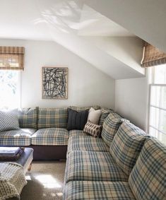 a living room with couches and pillows in front of a window on the wall