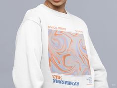 a woman wearing a white sweatshirt with an orange and blue graphic on the front that says one marvadors