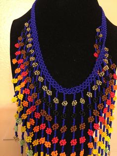 a multicolored beaded necklace is displayed on a mannequin