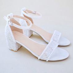 a pair of white shoes with bows on the heel and lace trimming around the toes