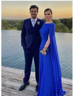 a man and woman in formal wear standing next to each other on a wooden dock