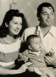 an old black and white photo of a man, woman and baby sitting on a couch