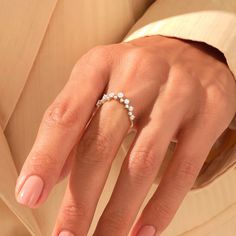 a woman's hand wearing a gold ring with three small white stones on it