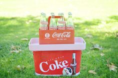 several bottles of coca - cola in a cooler on the grass