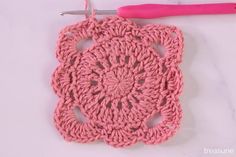 a crochet doily is shown with a pink crochet hook