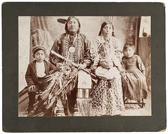 an old black and white photo of native american indians with two children in front of them