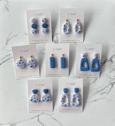 six pairs of blue and white ceramic earrings on display in front of cards with instructions