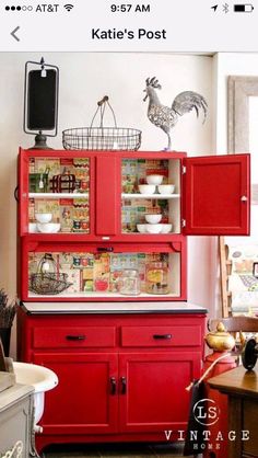 a red china cabinet with rooster figurines on top