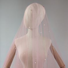 a mannequin wearing a pink veil with pearls on it