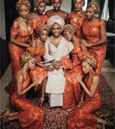 a group of women in orange dresses posing for a photo with one woman sitting on the floor