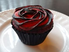 a chocolate cupcake with red frosting on a white plate