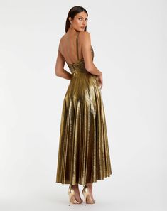 a woman wearing a gold metallic dress with open back and high heels on her feet