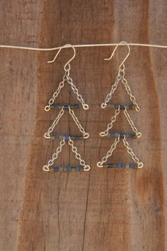 two pairs of earrings hanging from a string on top of a piece of wooden plank