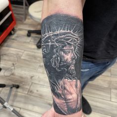 a man's arm with a tattoo of the statue of jesus holding a cross