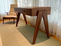 a wooden desk sitting on top of a rug in front of a curtained window