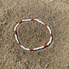 white seed beads with a pattern of shiny red, striped and solids strung on elastic please gently roll off and on to prolong its life handmade in venice, ca White Hand-strung Beaded Bracelets For Beach, White Hand-strung Beaded Bracelet For Beach, White Heishi Beads Bohemian Stretch Bracelet, Bohemian White Heishi Beads Stretch Bracelet, Casual White Beaded Bracelets For Festivals, White Beaded Bracelets For Beach With Round Beads, White Beaded Bracelets For The Beach, White Beaded Bracelet For The Beach, White Beaded Bracelet For Beach