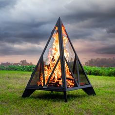 a fire pit in the middle of a field with dark clouds above it and grass on both sides