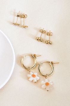 These small, handmade hoop earrings are here to compliment your spring outfit! If you love all things adorable and floral, these dainty earrings are for you! Also featuring our Starburst Stud Earrings, and Triple Ball Stud Earrings. The Daisy Hoop Earrings features a delicate daisy bead made of Mother of Pearl, perfect for spring and summer! These pretty earrings are sure to catch attention. Complete the look with our Daisy Necklace and Daisy Bracelet. Find more tiny hoops at Simple & Dainty! Daily Use Earrings, Earring Stack, Handmade Hoop Earrings, Daisy Charm, Daisy Bracelet, Types Of Gold, Daisy Necklace, Gold Filled Earrings, Pretty Earrings