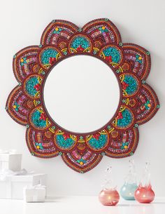 a decorative mirror hanging on the wall next to some vases and other items in front of it