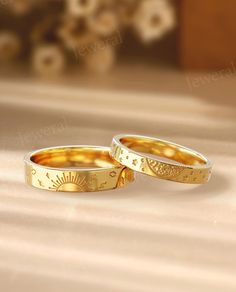 two gold wedding rings sitting next to each other