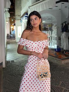 a woman in a polka dot dress is holding a purse