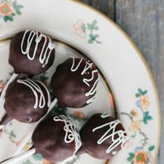 four chocolate covered cake pops on a plate with a fork in the middle and flowers around them