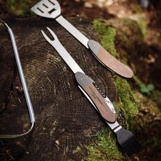 three knives and spatulas sitting on top of a tree stump