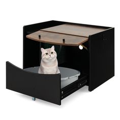 a white cat sitting in an open drawer on top of a black desk with a wooden table