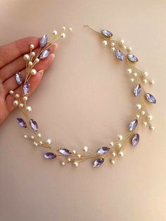 a close up of a woman's hand holding a bracelet with pearls and crystals